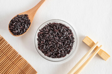 Black venereal rice in a glass bowl with chopsticks and a spoon of rice
