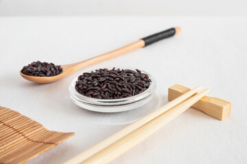 Black venereal rice in a glass bowl with chopsticks and a spoon of rice

