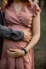 A man hugs the belly of a pregnant woman.