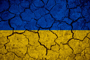 Ukrainian flag blue and yellow on a mud texture of dry cracks on the ground.	