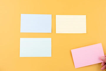 hand putting blank writing paper and three empty papers on a yellow background. space for text.