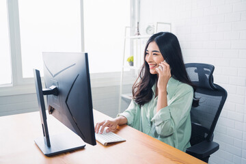 Beautiful Asian business woman work at home modern office, contacting mobile smartphone cheerful in success happy joyful excitement, smart plan strategies using computer internet networking technology