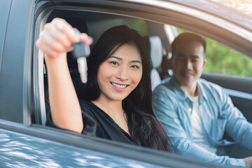 Asian woman buying or renting rental new car owner car key hand shake from sales seller, taking and passing driving license examination test happy cheerful smiling excited salesman sold car dealership