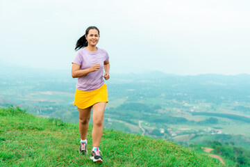 Asian women trail runners training on a high mountain. The back view is high mountain, beautiful scenery. In the evening the air is fresh and atmosphere is good.