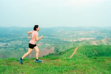 Obraz premium Asian women runner training on a high mountain. The back view is high mountain, beautiful scenery. In the evening the air is fresh and atmosphere is good.