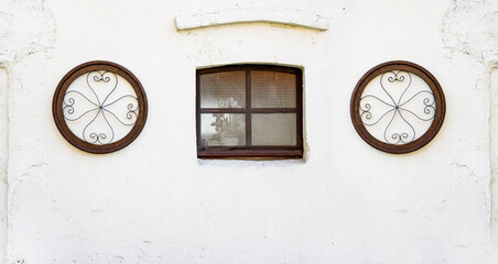A brown wooden window of an old house, with cottage decoration on the white washed wall - old wall of cottage house - obrazy, fototapety, plakaty