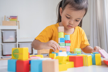Asian baby girl playing alone. Little kid plays building blocks.