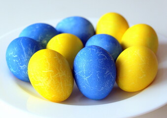Happy Easter. Horizontal poster with cute painted yellow and blue eggs on a white plate.