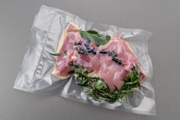 Chicken thighs with rosemary sage and spices in vacuum packed sealed for sous vide cooking isolated on Grey background in top view