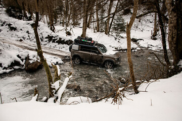 high angle view on off-road vehicle driving through a mountain river at winter