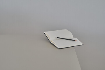 Notebook or notepad and black pencil on the corner of the gray table . Freelance desktop for home or office. Mock up in copy space office background. Shallow depth of field. Focus on pencil