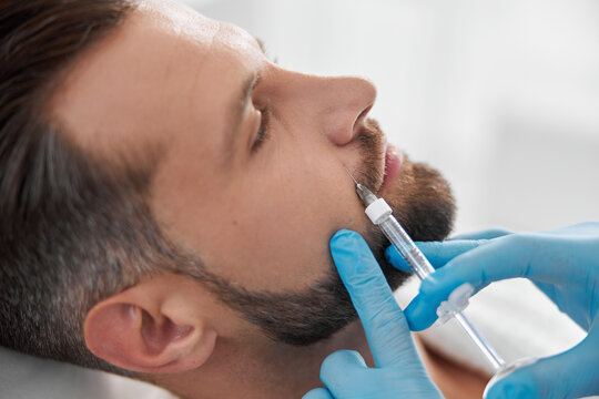 Mature person with beard undergoes nasolabial fold filler procedure with skilled beautician in salon