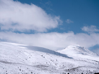Fototapeta na wymiar Mountains with fresh snow and blue sky with white clouds. Sierra de Guadarrama, Madrid, Spain.