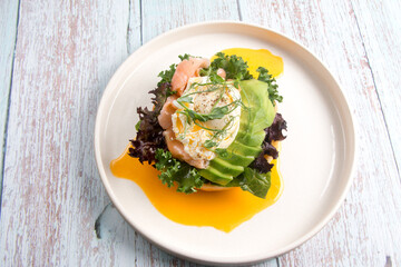 restaurant dish Brioche with poached egg with salmon and avocado. Delicious bread with greens