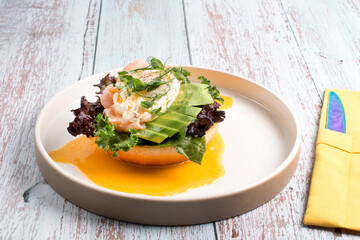 restaurant dish Brioche with poached egg with salmon and avocado. Delicious bread with greens