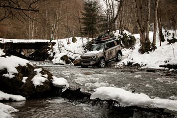 off-road vehicle drives through a mountain river at winter
