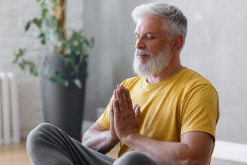 senior yoga, a man with gray hair meditates and does breathing exercises. sports fitness and...