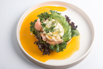 restaurant dish Brioche with poached egg with salmon and avocado. Delicious bread with greens
