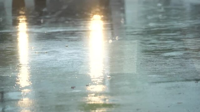 Slow motion of rain falling on the asphalt and cars passing through the puddles.