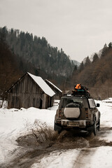 rear view of off-road car ride on snowy road at mountains. Mountain tourism transport.