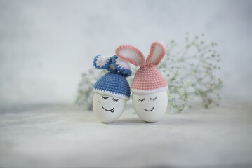 easter eggs in blue and pink bunny hats on flower background