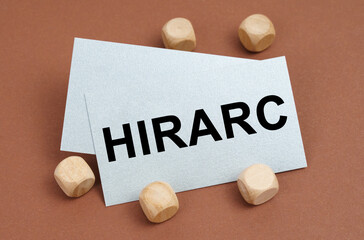On a brown surface, wooden cubes and a business card with the inscription - HIRARC