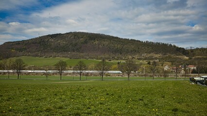 Eine ICE-Zugdurchfahrt vor dem Grossen H&ouml;rselberg an einem Fr&uuml;lingstag.
