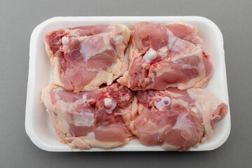 Chicken thighs in food plastic tray for sale in supermarket, isolated on gray background, clipping path