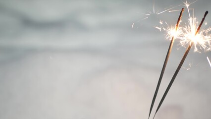 Sparkler firework burning in snow, New Year or Christmas bengal lights. Snowflakes as background. Winter Xmas holiday magic, sparkles, flakes, and golden fire stars light. Seamless looped cinemagraph.