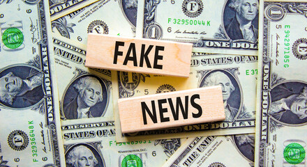 Fake news symbol. Wooden blocks with concept words Fake news on beautiful background from dollar bills. Business media and fake news concept. Copy space.
