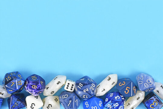 Different roleplaying RPG dice at bottom of blue background with blank copy space