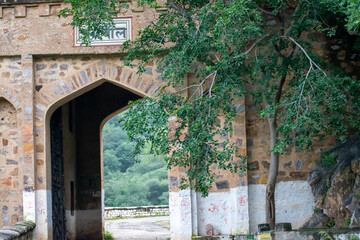 Big stone brick gates painted white and brown enroute wildlife safari in alwar rajasthan.Abandoned stone gate represents the old kingdom architecture and history.Gate passes through wildlife sanctuary