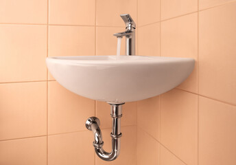 Bathroom beige interior with sink and faucet with flow of water