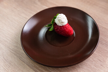 one and two strawberries with whipped cream on a plate