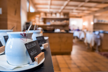 San Candido, Italy. March 18, 2022. White ceramic jars with labels placed on counter at restaurant, White jars with labels in plates placed on table at hotel