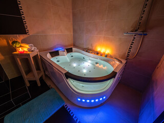 Illuminated massage bath with water. Luxury bathroom. Burning candles.