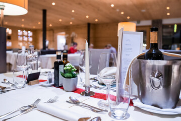 San Candido, Italy. March 18, 2022. Wine bottle in ice bucket with luxury elegant table setting in modern restaurant, Wine bottle in bucket on table with place setting in hotel