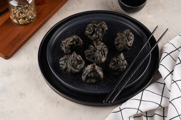 Traditional Georgian dish, khinkali Kalakuri, black dumplings stuffed with minced meat on black plate on beige colored background