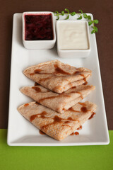 Pancakes with sour cream and jam on white plate