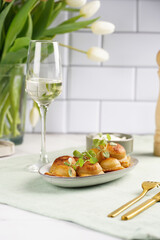 Deep fried traditional italian dish - ravioli, dumplings stuffed with minced meat, oregano branch, sour cream, a glass with champagne on green table cloth