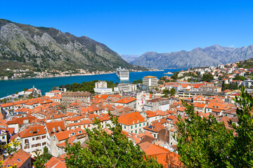 Naklejka na ściany i meble Kotor, Montenegro, Europe. Bay of Kotor on Adriatic Sea. Roofs of the historical buildings in the old town, sea and mountains in the background. Clear blue sky, sunny day