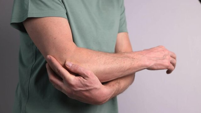 Man suffering from elbow pain and holding painful hand closeup. Hand injury. Health care, joint diseases concept.