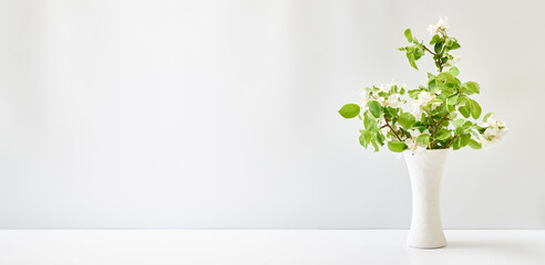 Spring flowers in a vase on a white table. Easter background with copy space