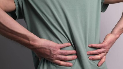Lower back pain. Man hands holding painful spot closeup. Sedentary lifestyle, injury, chronical illness, inconvenient posture.