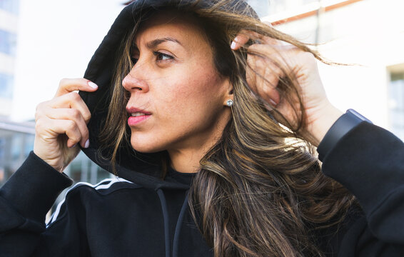 Sportswoman putting on hood on street