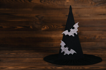 Witch hat with bats print on brown textured wooden background. Halloween holiday concept.Place for...