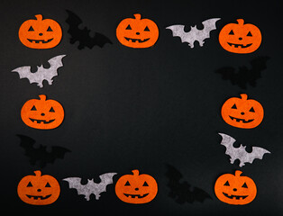 Frame of figures of orange pumpkins and bats on a black background. DIY Halloween decor.Holiday card.Halloween holiday concept.Place for copy.Place for text.Top view.