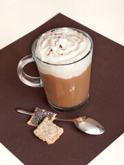 Coffee in glass cup with whipped cream and poppy seed cookies.