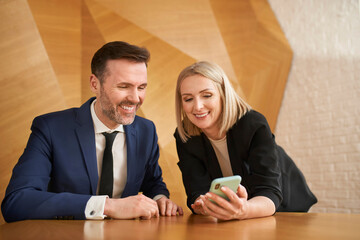 Businessman and businesswoman having fun looking on mobile phone sharing something