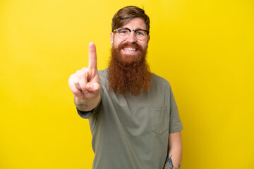 Redhead man with beard isolated on yellow background showing and lifting a finger